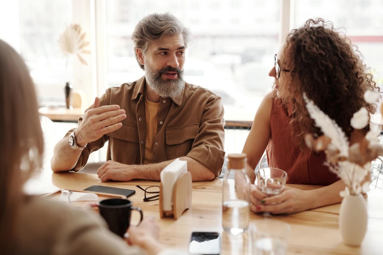 ludzie rozmawiający przy stole - charakterystyka języka mówionego